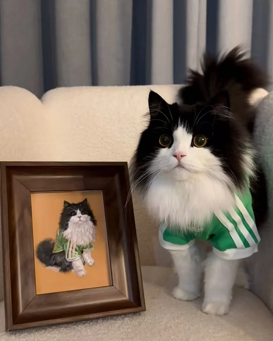 Black and white cat beside its custom framed pet portrait